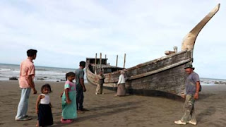 Wisatawan melihat kapal kayu yang pernah digunakan pengungsi Rohingya di Pantai