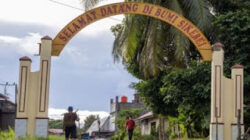 Warga melintas di gerbang pintu masuk di Tuapejat, Kabupaten Kepulauan Mentawai, Sumbar.