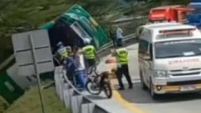 Polisi mengevakuasi bus wisata yang terguling.