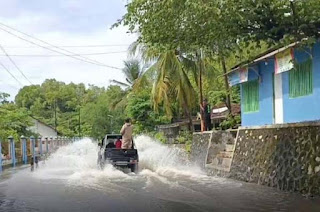 Sebuah mobil menerobos banjir yang merendam jalan utama.