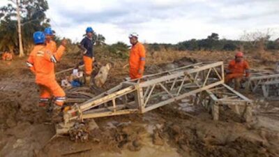 Di tengah medan yang berlumpur, petugas PLN melakukan perakitan tower darurat