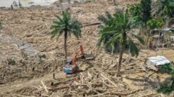 Petugas mengoperasikan eskavator untuk membersihkan jalan akses antardesa Aceh