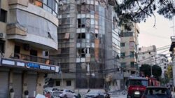 Puing-puing berserakan di jalan di samping gedung apartemen