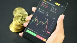 Tangan memegang smartphone menampilkan transaksi digital saldo dana.