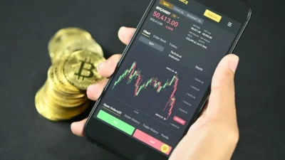 Tangan memegang smartphone menampilkan transaksi digital saldo dana.