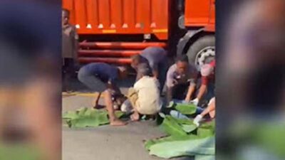 Petugas dibantu warga mengevakuasi dua pemotor yang tewas terlindas truk