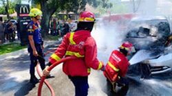Personil Damkar Padang memadamkan api yang membakar mobil.
