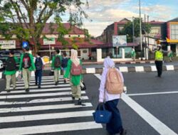 Polisi Bantu Pelajar Menyeberang di Jalan Padat